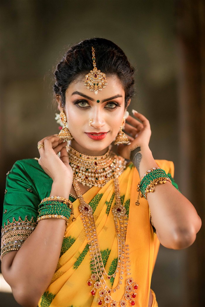 Bridal portrait in yellow saree with gold jhumka earrings and layered necklace, Ashvi Beauty Care Jaffna